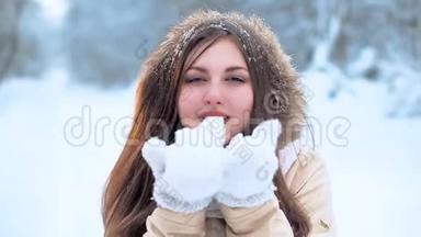 戴着白色围巾的小女孩走在森林里，对着镜头吹着一把雪。